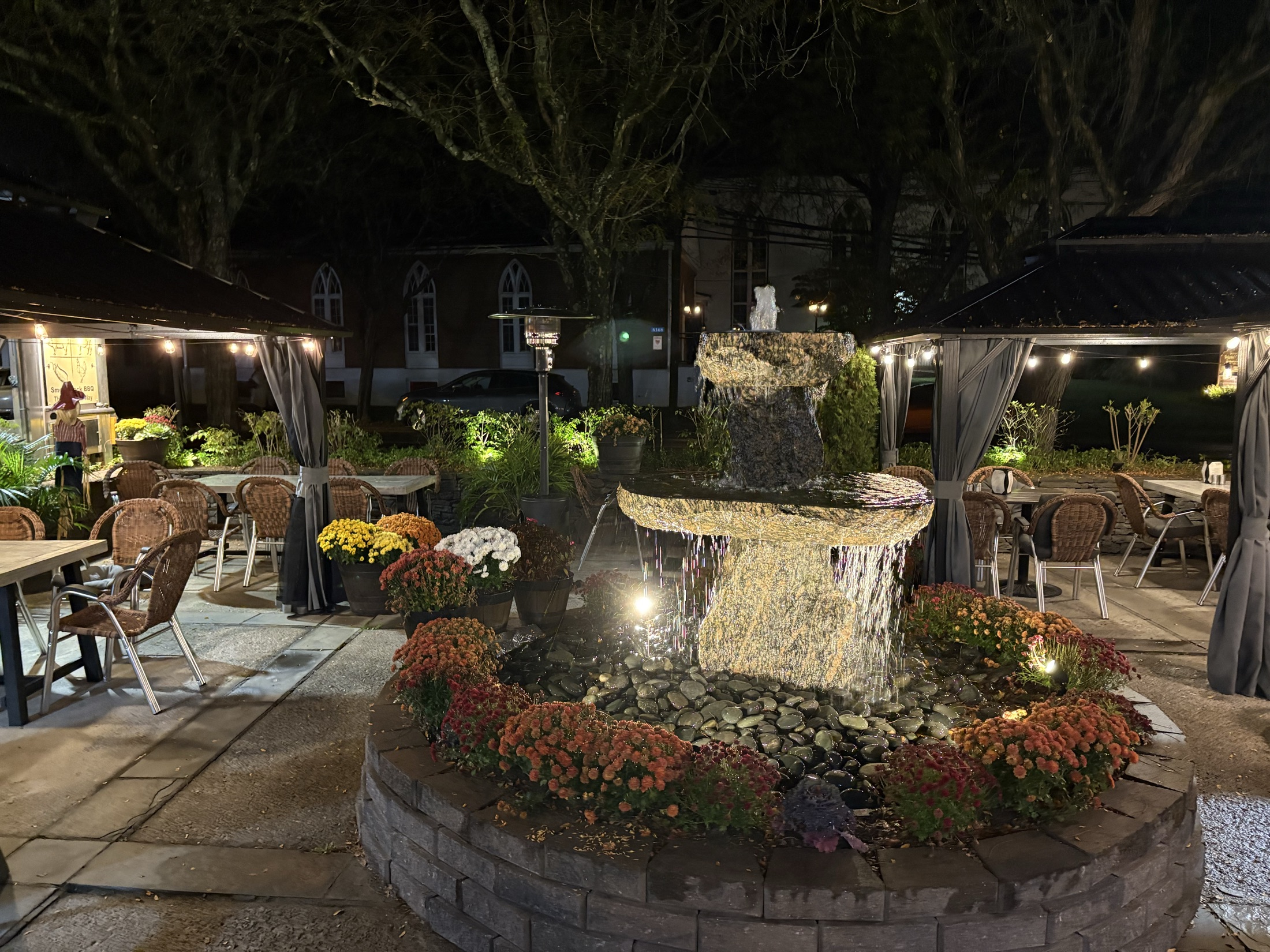 Smoky Rock BBQ evening patio with fountain, flowers, and canopy seating